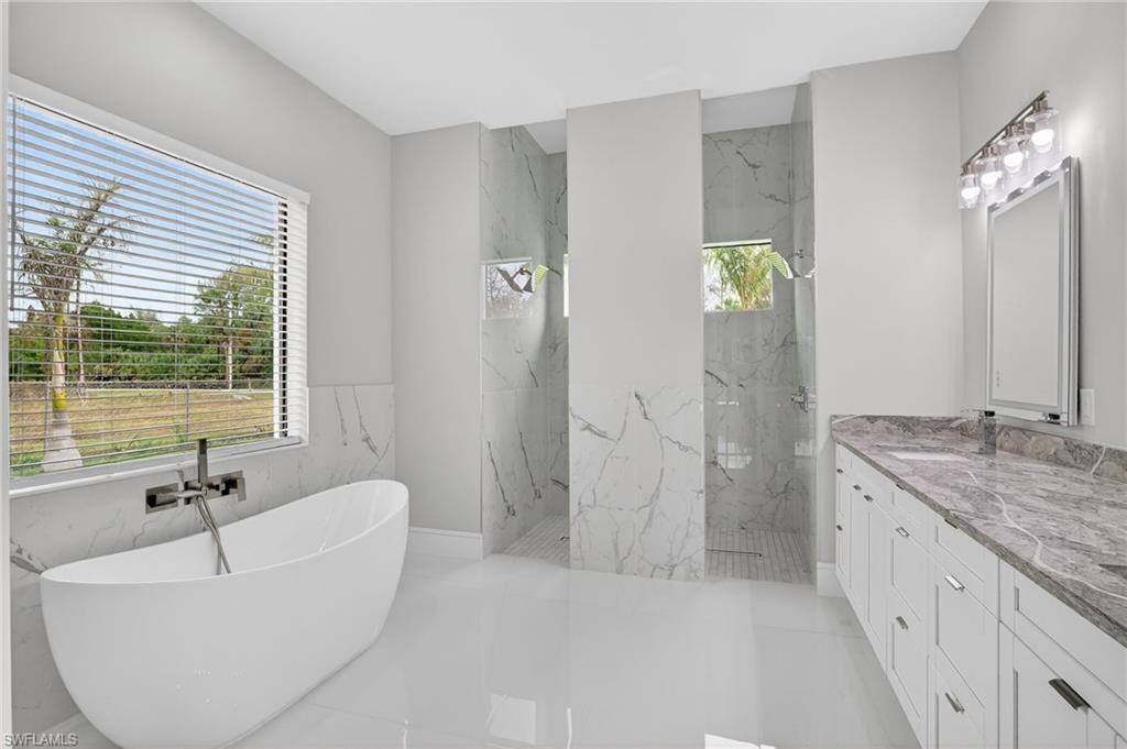 563 15th Street Northwest Naples, FL 34120 - Photo 5 of 33 Full bathroom with a freestanding tub, a marble finish shower, and vanity