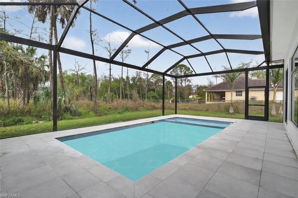 563 15th Street Northwest Naples, FL 34120 - Photo 10 of 33 Outdoor pool with a sunroom, a lanai, a patio area, and a lawn