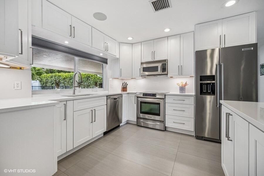746 Southwest 2nd Street Boca Raton, FL 33486 - Photo 9 of 54 a kitchen with white cabinets and stainless steel appliances