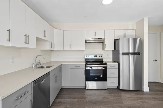 a kitchen with stainless steel appliances a refrigerator stove and white cabinets