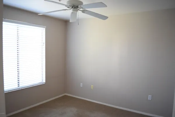 an empty room with a window and a fan