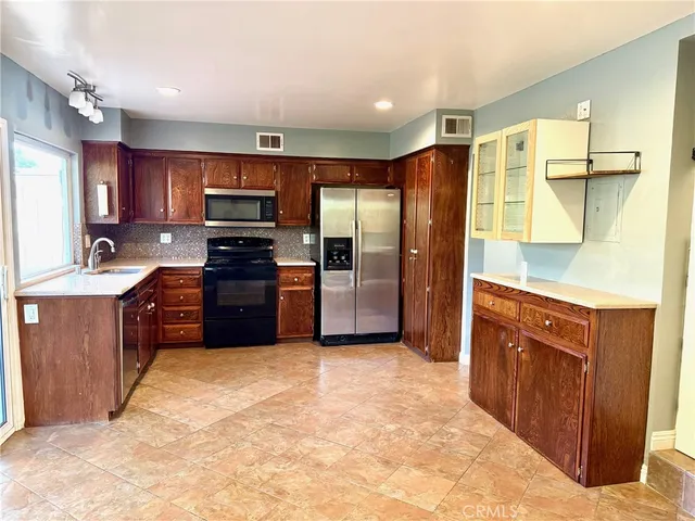 a large kitchen with stainless steel appliances granite countertop a refrigerator a sink a stove a microwave and island