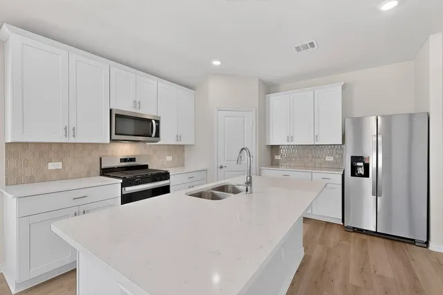 a kitchen with granite countertop a refrigerator stove and sink