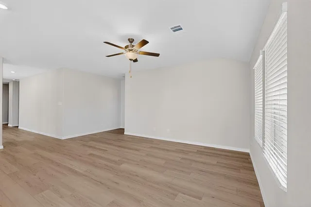 a view of room with hardwood floor and a ceiling fan