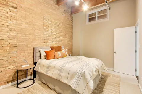 a bedroom with a bed and a brick wall