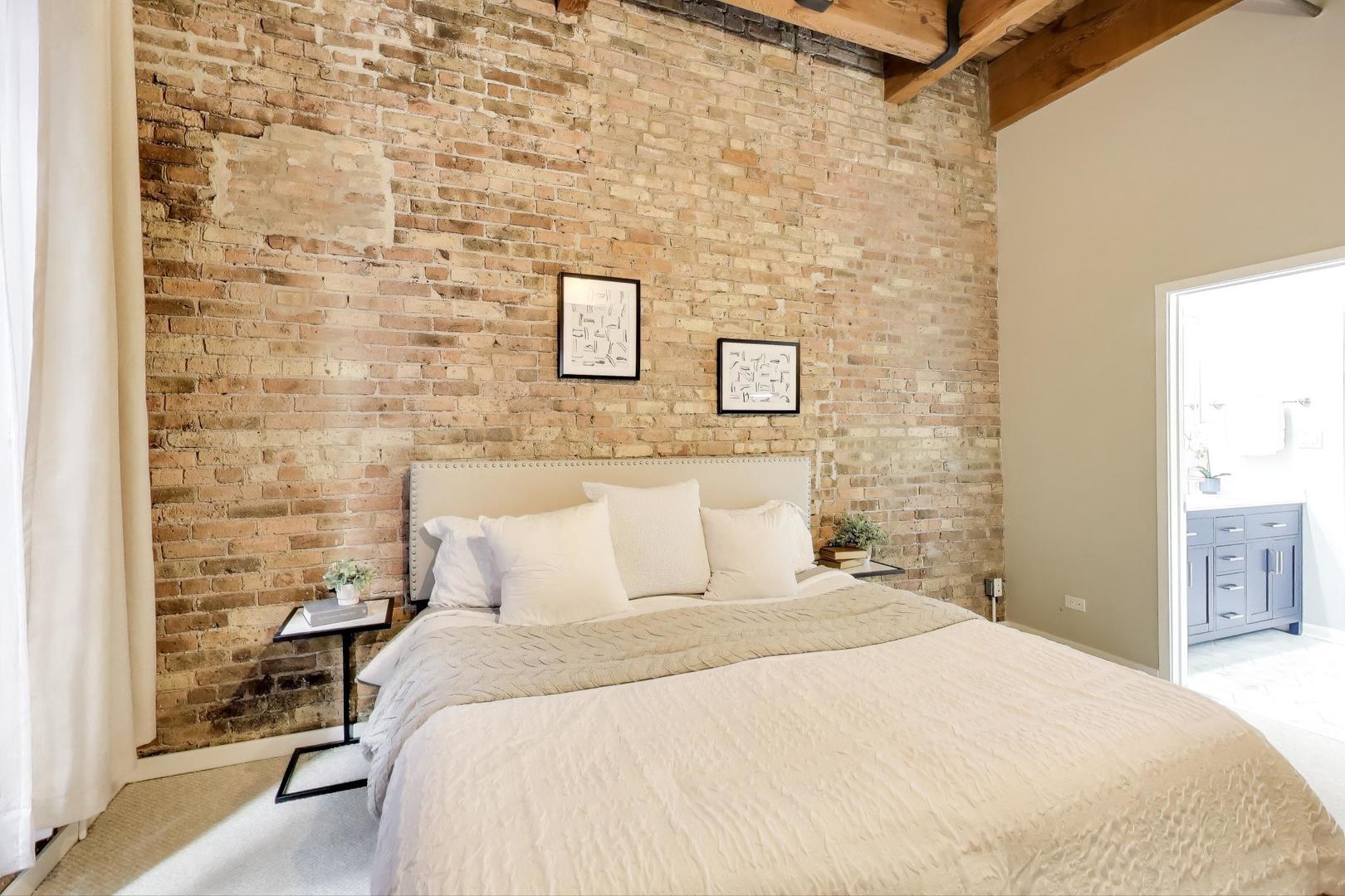 300 West Grand Avenue, Unit 210 Chicago, IL 60654 - Photo 8 of 20 a bedroom with a bed and a brick wall