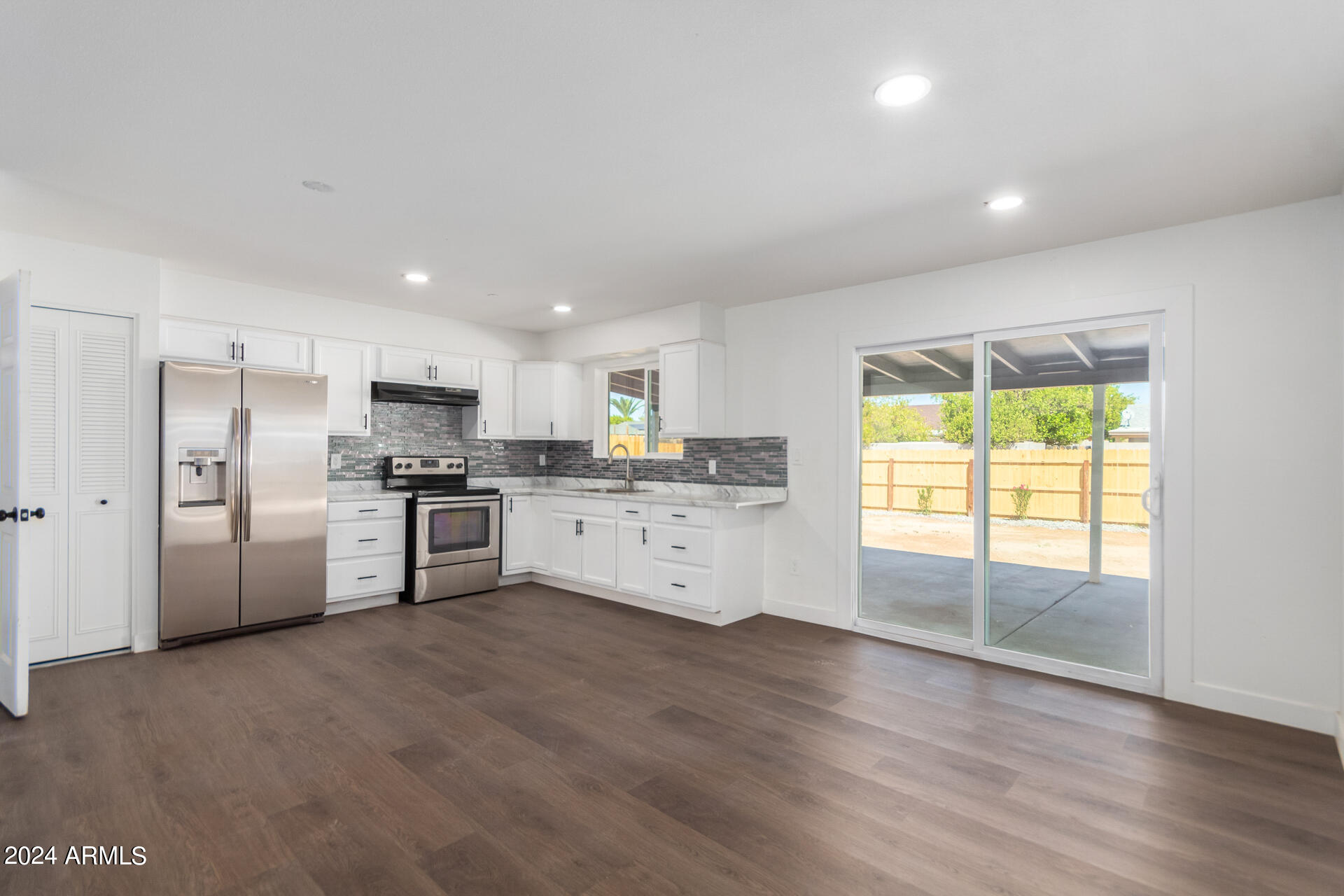 5338 West Coronado Road Phoenix, AZ 85035 - Photo 8 of 29 a kitchen with stainless steel appliances kitchen island granite countertop a stove a sink a refrigerator with white cabinets and wooden floor
