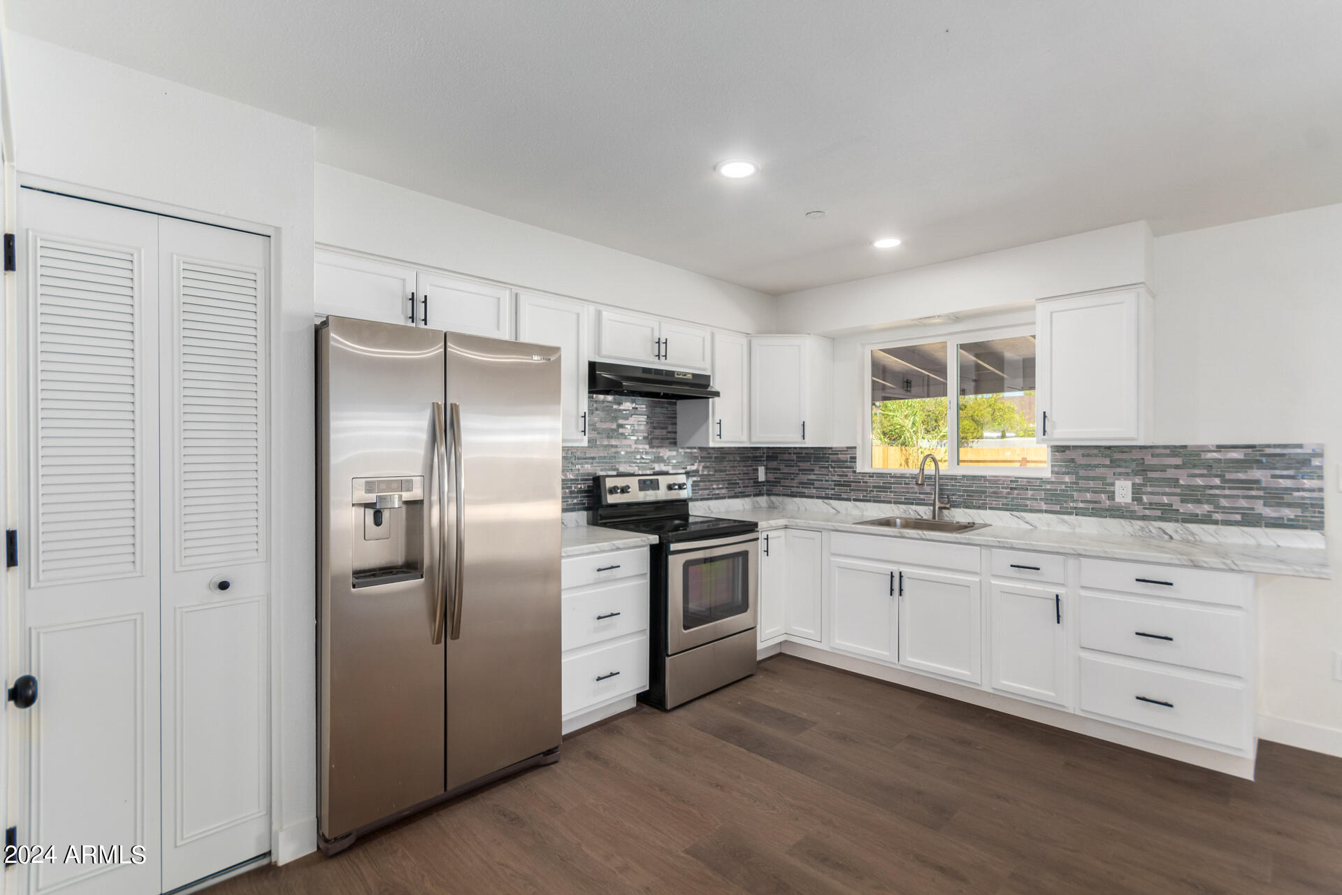 5338 West Coronado Road Phoenix, AZ 85035 - Photo 10 of 29 a kitchen with stainless steel appliances granite countertop a refrigerator a stove a sink and white cabinets