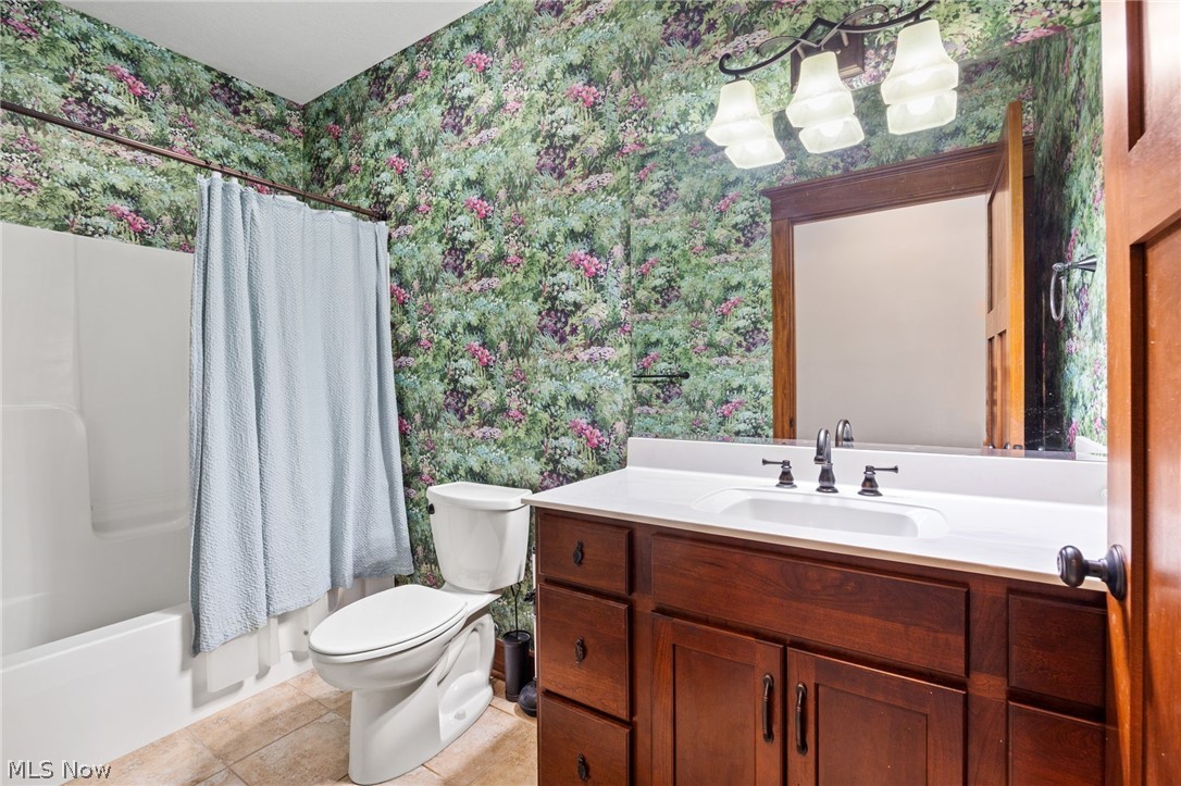 6925 River Styx Road Medina, OH 44256 - Photo 24 of 49 Bathroom featuring a white bathtub and toilet, a dark wood vanity with a white countertop and integrated sink, a framed mirror, and a three-light vanity fixture