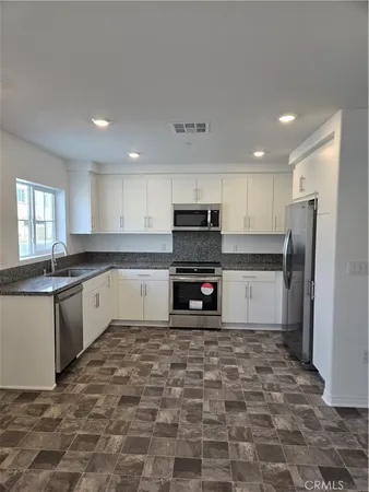 a large kitchen with granite countertop a stove a sink a refrigerator a microwave and cabinets