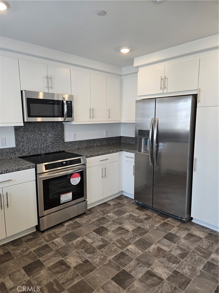 7281 Olive Grv Street Riverside, CA 92507 - Photo 5 of 27 a kitchen with granite countertop a refrigerator and a stove top oven