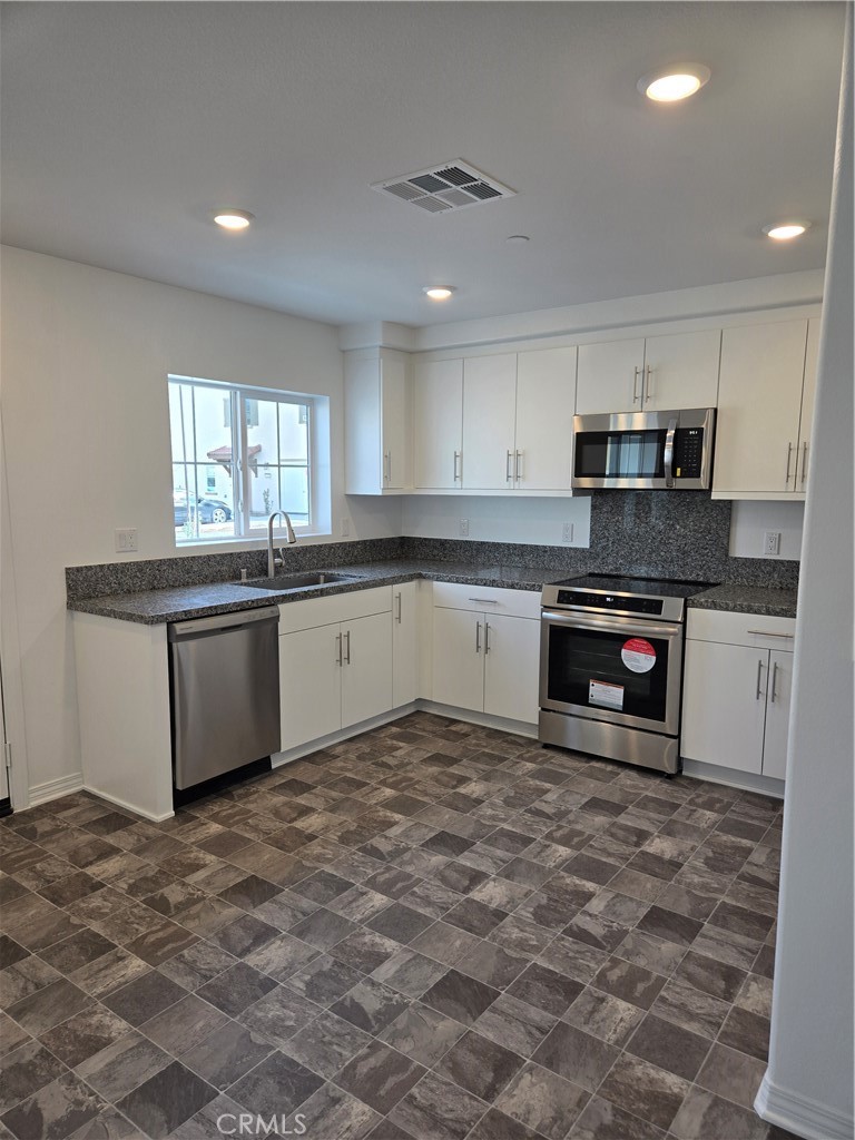 7281 Olive Grv Street Riverside, CA 92507 - Photo 6 of 27 a kitchen with stainless steel appliances granite countertop a stove a sink and a microwave
