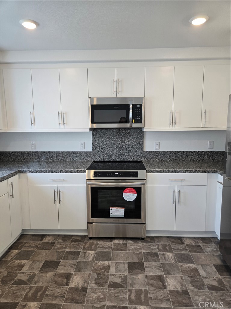 7281 Olive Grv Street Riverside, CA 92507 - Photo 7 of 27 a kitchen with granite countertop a stove a sink and a microwave