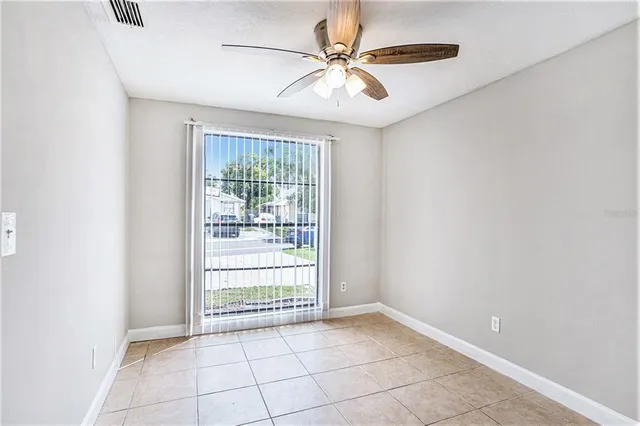 an empty room with chandelier fan and windows