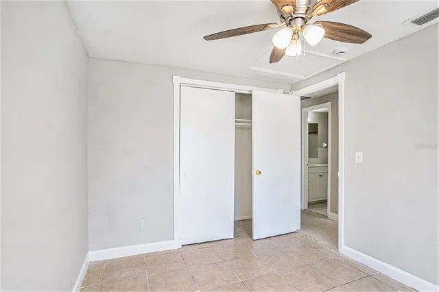 an empty room with a chandelier fan and windows