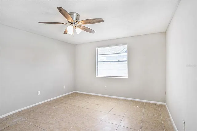 an empty room with a window and a ceiling fan