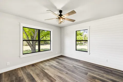 an empty room with windows and ceiling fan