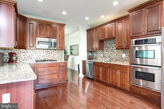 a kitchen with stainless steel appliances granite countertop wooden cabinets a stove top oven a sink and dishwasher