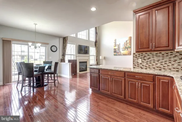 a kitchen with stainless steel appliances granite countertop wooden floors wooden cabinets dining table and chairs