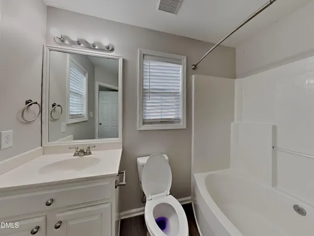 a bathroom with a granite countertop sink toilet a mirror and bathtub