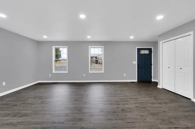 an empty room with wooden floor and windows