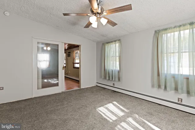 an empty room with wooden floor mirror and windows