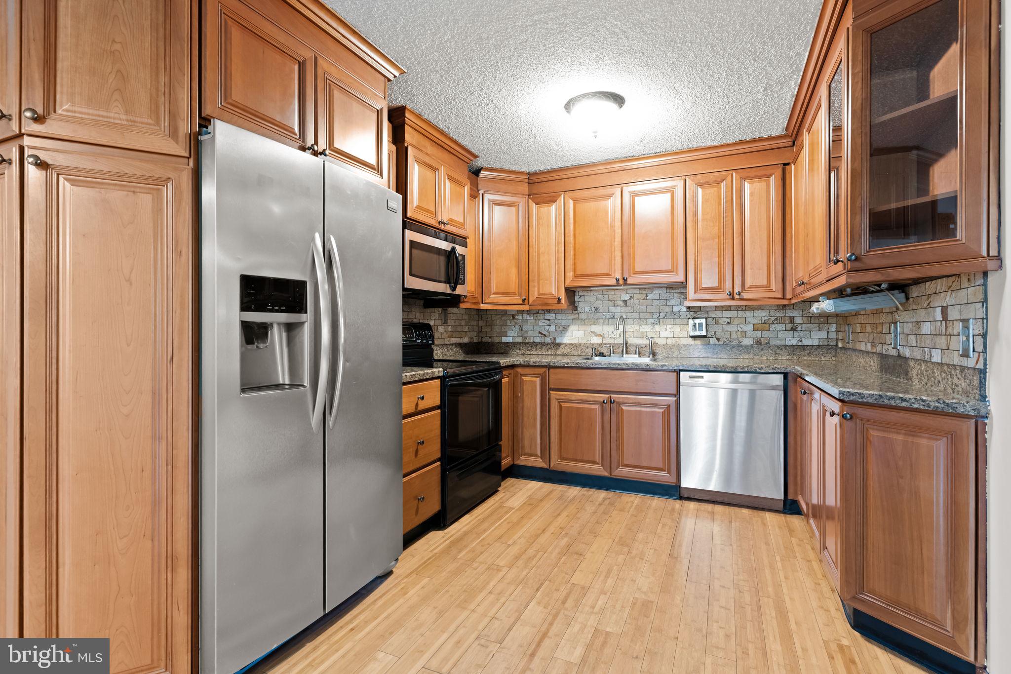 212 Plumbridge Drive Levittown, PA 19056 - Photo 4 of 19 a kitchen with stainless steel appliances granite countertop a refrigerator a sink dishwasher a stove with wooden cabinets and floor