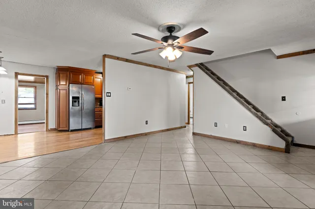 a view of an empty room with window and chandelier fan