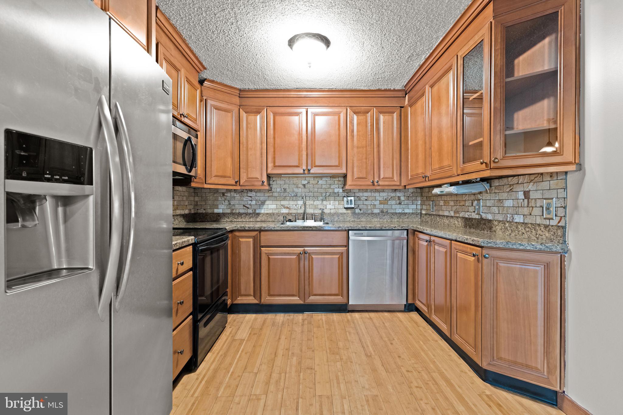 212 Plumbridge Drive Levittown, PA 19056 - Photo 5 of 19 a kitchen with stainless steel appliances granite countertop a refrigerator a sink dishwasher a stove and white countertops with wooden floor