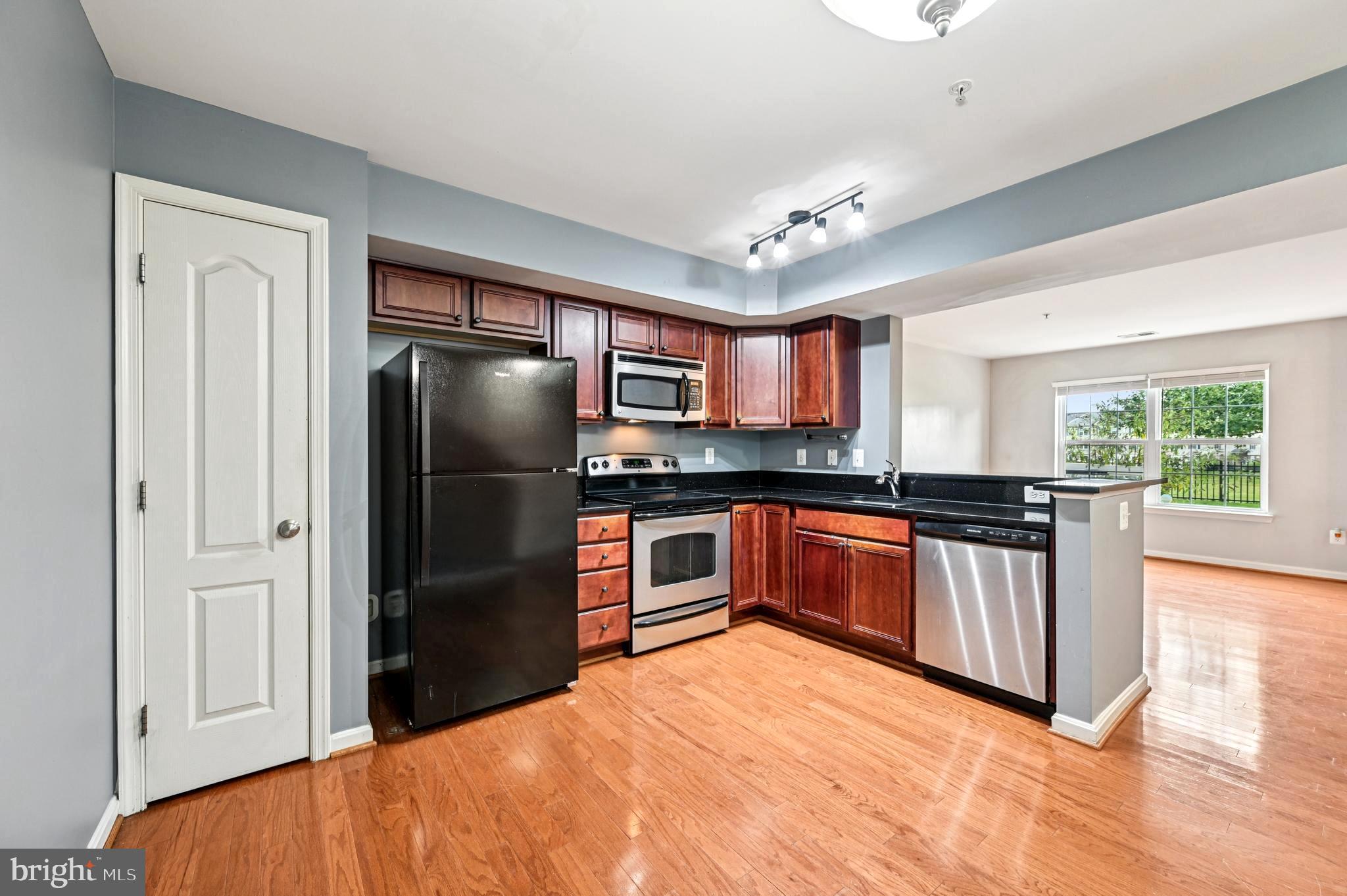 6467 Cornwall Drive, Unit 56 Eldersburg, MD 21784 - Photo 17 of 35 a kitchen with stainless steel appliances granite countertop a refrigerator a stove a sink and dishwasher with wooden floor
