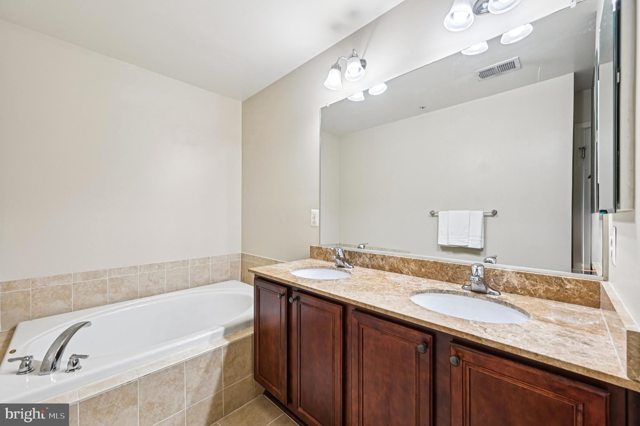 6467 Cornwall Drive, Unit 56 Eldersburg, MD 21784 - Photo 7 of 35 a bathroom with a granite countertop bathtub sink double vanity and mirror