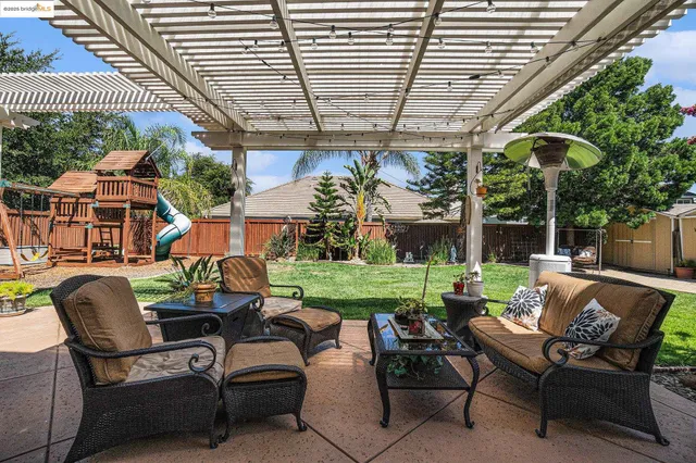 a view of a patio with table and chairs potted plants and a large tree