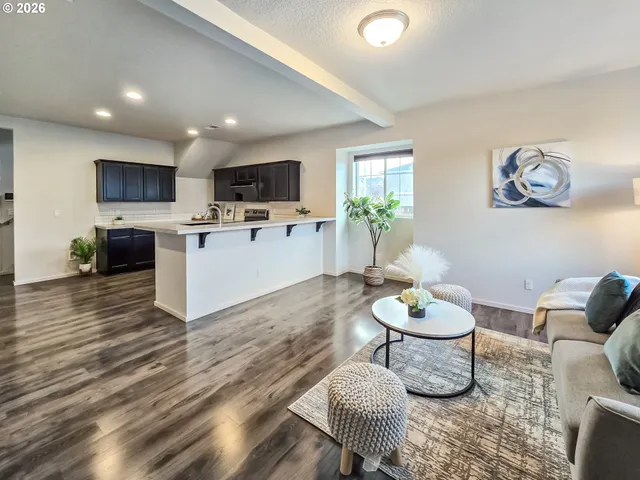 a living room with furniture a flat screen tv and kitchen view