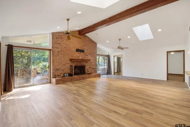 an empty room with wooden floor fireplace and windows