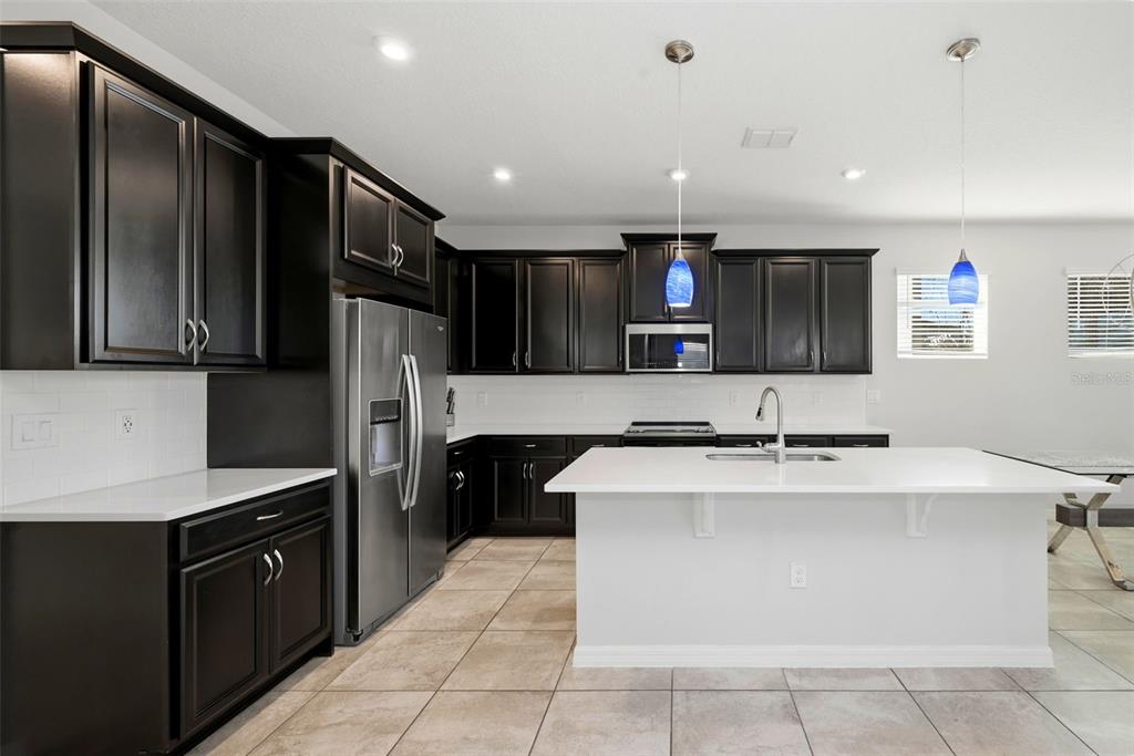 16662 Wingspread Loop Winter Garden, FL 34787 - Photo 7 of 24 a large kitchen with stainless steel appliances kitchen island granite countertop a refrigerator and a sink