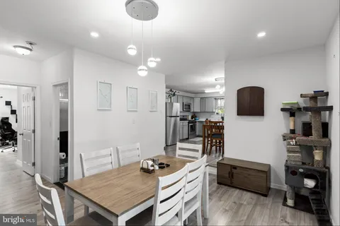 a kitchen with stainless steel appliances granite countertop a stove top oven a sink a refrigerator and white cabinets with wooden floor