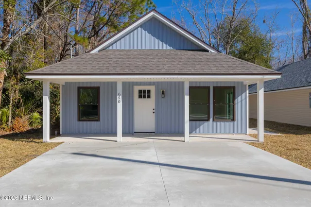 a front view of a house with a yard and potted plants