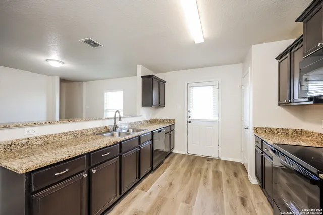 a kitchen with granite countertop cabinets stainless steel appliances and a sink