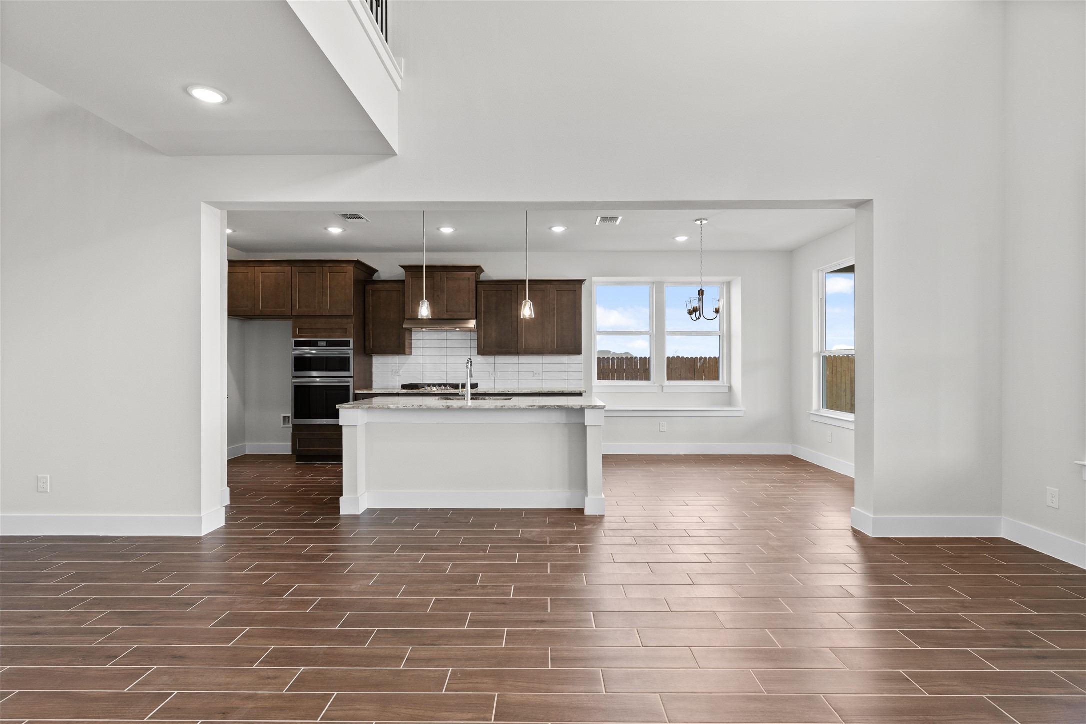 19705 Domino Champ Road Pflugerville, TX 78660 - Photo 15 of 38 Polished tile flooring flows seamlessly through this open-concept layout beneath towering double-height ceilings.