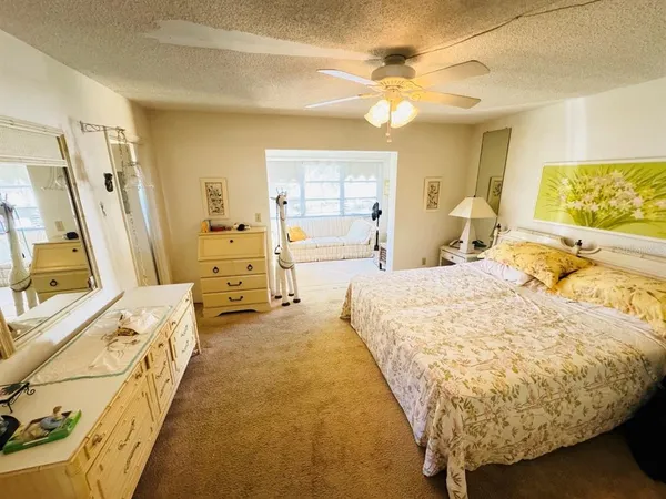 a spacious bedroom with a bed and a flat tv screen on dresser