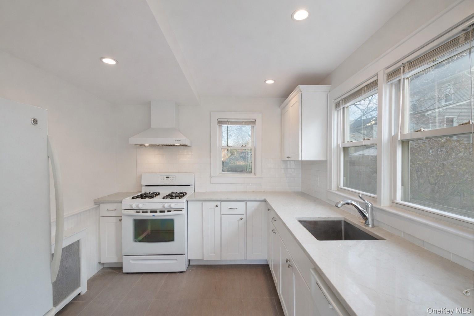 a white kitchen with a stove top oven sink and window