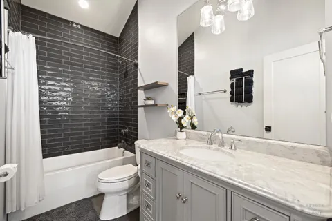 a bathroom with a granite countertop sink a toilet a mirror and shower