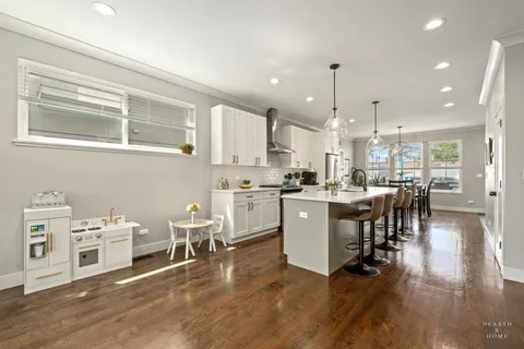 a kitchen with a table chairs wooden floors and a view of living room