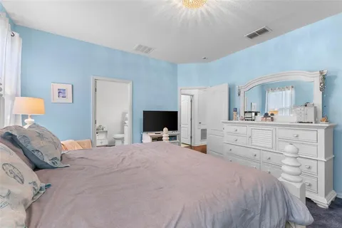a bedroom with a bed a mirror and a flat tv screen on dresser