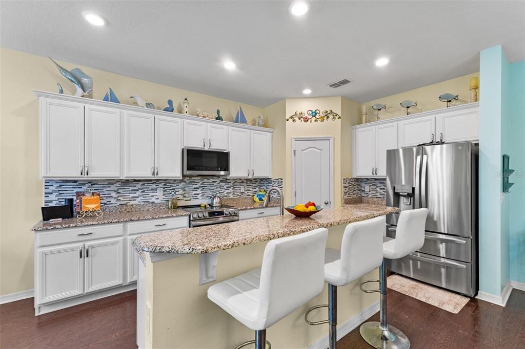 3240 Macintosh Road Land O Lakes, FL 34639 - Photo 5 of 32 a kitchen with stainless steel appliances a refrigerator a stove a sink dishwasher and white cabinets with wooden floor