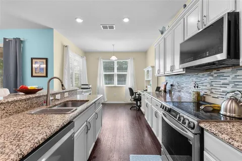 a kitchen with granite countertop a sink and a stove top oven