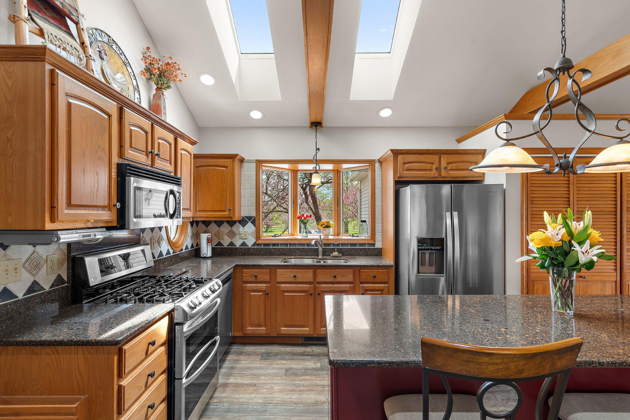 8 Smoke Road Valparaiso, IN 46385 - Photo 11 of 60 a kitchen with stainless steel appliances granite countertop a refrigerator a sink dishwasher a stove and a dining table with wooden floor
