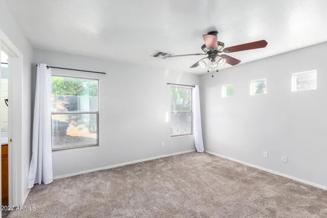 an empty room with windows and fan