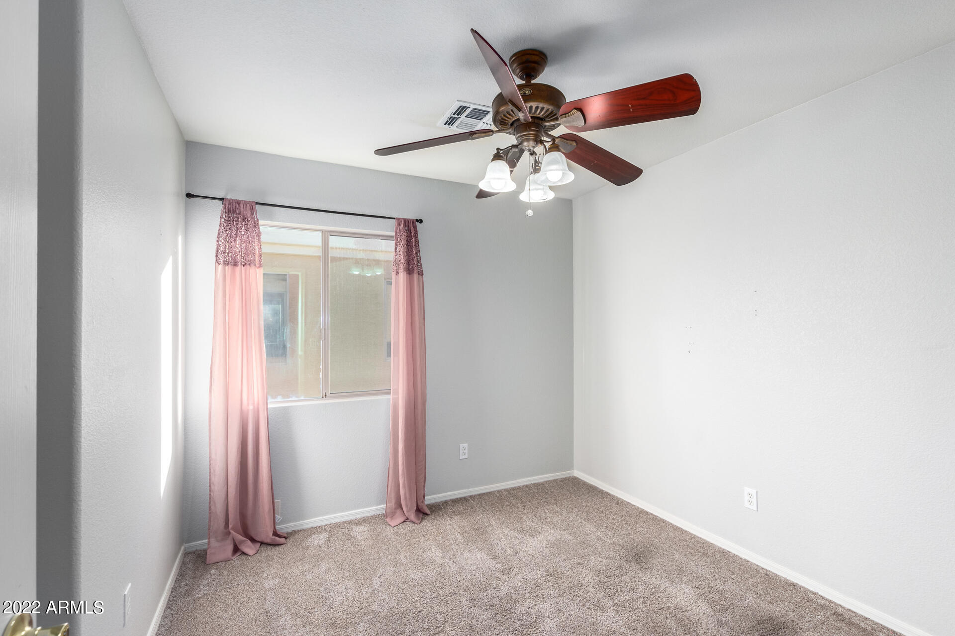 2609 South Devonna Lane Tolleson, AZ 85353 - Photo 20 of 30 an empty room with windows and fan