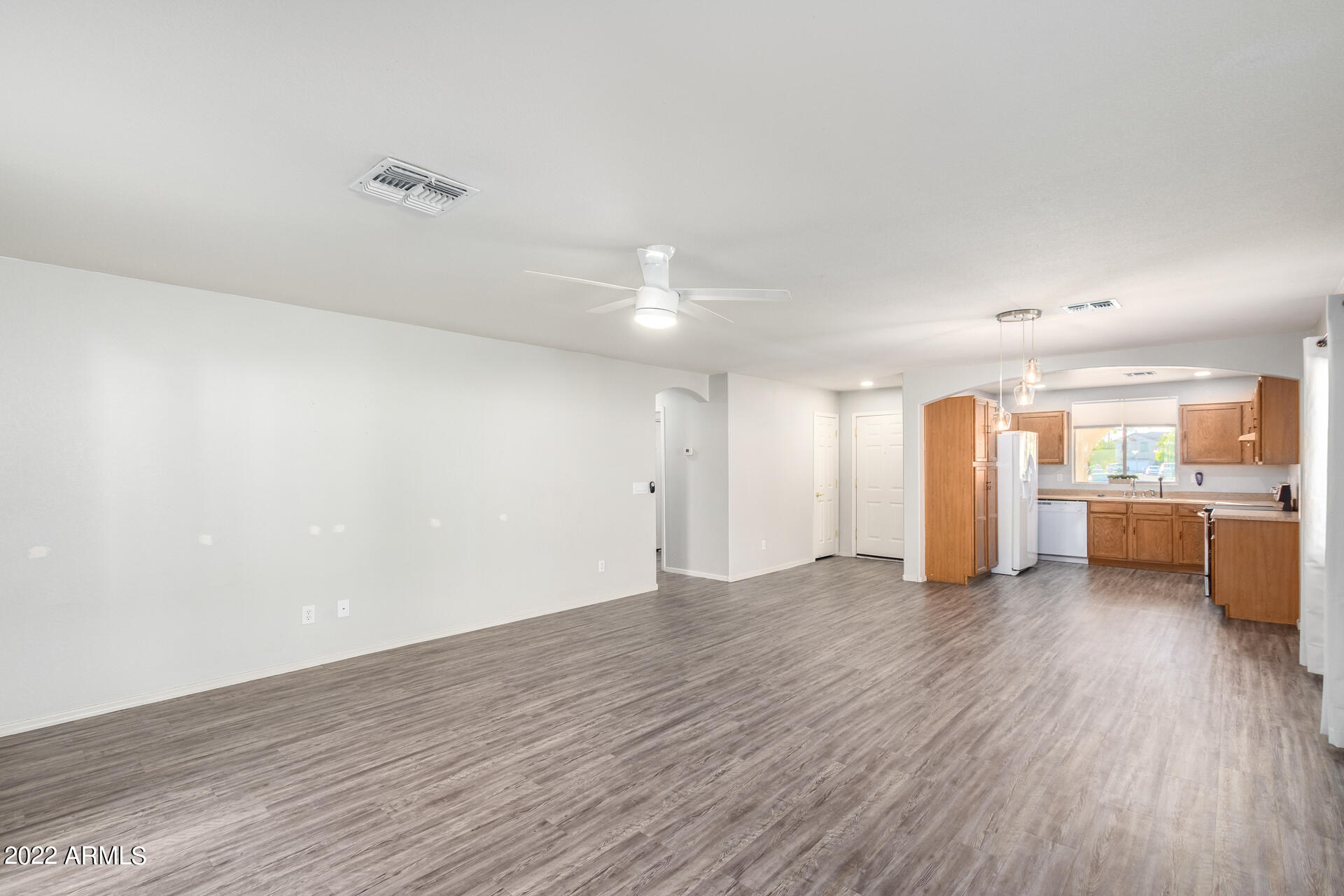 2609 South Devonna Lane Tolleson, AZ 85353 - Photo 5 of 30 a view of an empty room with wooden floor and a kitchen